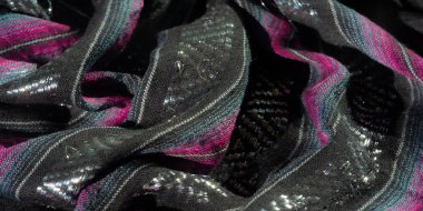 Zıt pembe ve mavi çizgili siyah kumaşlar örülmüş metalik aksanlı ayrıntılı işçilik sergiliyor. Yumuşak doku ve kıvrımlar zarif ve dinamik bir görsel oluşturur.