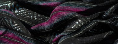 Pembe ve mavi çizgili bulanık siyah kumaş iç içe geçmiş yansıtıcı liflerden dolayı parlak bir yüzeye sahip katlanmış kumaş, renkli ve dokuların çok güzel bir karışımını ve canlı zıtlıkları gösteriyor.