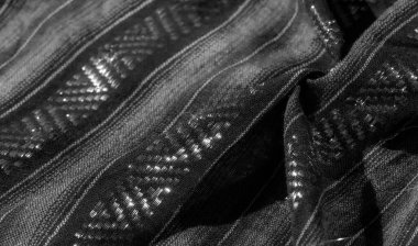 Dokulu çizgileri ve parıldayan geometrik şekilleri olan siyah kumaşın bulanık görüntüsü. Kumaşın üzerindeki ışık oyunu detaylı tasarıma zarif ve modern bir dokunuş ekler..
