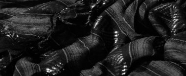 Dikey çizgileri ve üçgen desenleri olan bulanık gri pullu kumaş, karışık dokular ve ışığı hassas bir şekilde yakalayan yansıtıcı detaylar..