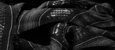 Karmaşık dikey çizgileri ve yansıtıcı ipliklerle örülmüş siyah bir kumaş. Işıldayan bir efekt ekliyor. Işığın ve gölgenin etkileşimi desenli desenleri geliştiriyor.