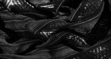 Karmaşık dikey çizgileri ve yansıtıcı ipliklerle örülmüş siyah bir kumaş. Işıldayan bir efekt ekliyor. Işığın ve gölgenin etkileşimi desenli desenleri geliştiriyor.