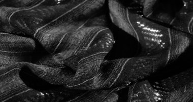 Çarpıcı zikzak desenleri ve dikey çizgileri olan bulanık gri pullu kumaş. Yansıtıcı ipliklerle ve eşsiz bir tasarım için dokulu detaylarla geliştirilmiş..