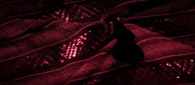 Bulanık kırmızı kumaşın parlak detaylarla dolu zengin dokusu, karmaşık desenleri ve parlak iplikleri aydınlatan yakın plan çekilir. Kumaş yumuşak kıvrımlar halinde akıyor.