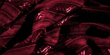 Karmaşık desenleri ve parlak dokusu olan kırmızı kumaşın bulanık yakın çekimi. Yumuşak kıvrımlar, yansıtıcı yüzeyle güçlendirilmiş lüks bir his yaratıyor.