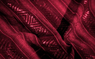 Parlak dokuma elementleri ve yansıtıcı röfleleri olan zengin kırmızı kumaştan bir bulanıklık. Karmaşık desenler ve derin tonlar görsel olarak büyüleyici ve lüks bir doku yaratıyor.