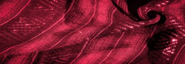 Karmaşık dokuma desenleri olan çarpıcı kırmızı bir kumaş ve lüks dokusunu ön plana çıkaran parlak, yansıtıcı bir kaplama. Kumaşın kıvrımları ve yansıtıcı detayları çekime derinlik ve boyut ekler.