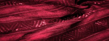 Parlak, yansıtıcı detaylarla karışık dokuma desenleri içeren kırmızı kumaş bulanıklığı. Kumaş yumuşak bir şekilde örtülmüş, bu lüks tekstil içinde hem dokusu hem de parıltısı sergileniyor.