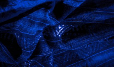 Bu mavi kumaşın parlak dokusu ve karmaşık dokusu büyüleyici ve katmanlı bir görünüm yaratır. Işıldayan ipliklerle vurgulanan kumaş, derinliği ve hareketi çağrıştırıyor.,
