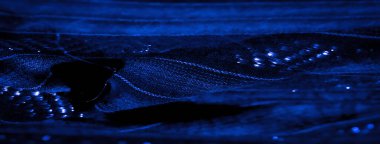 Bu mavi kumaşlar üzerindeki ışık ve karanlık zıtlıkların etkileşimini bulanıklaştırarak karmaşık dokuma desenini ve ince parıltısını vurguluyor, modern zarafeti çağrıştırıyor..