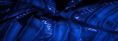 Işıkta parlayan desenleri olan koyu mavi kumaşı bulanıklaştırır. Gölgeler ve dalgalı yüzeyinde parlayan gölgeler sunar..