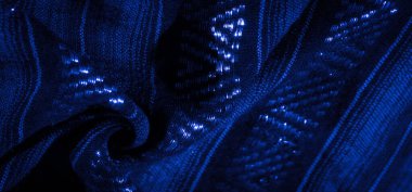 Katlanmış mavi bir kumaşın bulanık görüntüsü ve karmaşık parlak detaylar. İnce gölgeler ve gölgeler, kumaşın dokusunu ve zarafetini gösteren görsel olarak çekici bir kompozisyon oluşturuyor..