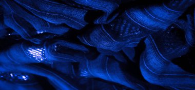 Karmaşık dokuma desenleri ve yansıtıcı ipliklerle donanmanın mavi kumaşının bulanık bir yakın çekimi büyüleyici bir doku yaratıyor ve kıvrımların derinliğini vurguluyor.