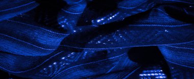 Karmaşık desenleri ve parıldayan aksanlarıyla mavi kumaşın bulanık görüntüsü görsel olarak dinamik bir etki yaratıyor. Işık yansımaları, kumaşın derinliğini ve dokusunu arttırır.