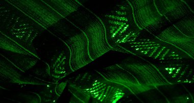 Parlak yeşil dokuların parlayan ipliklerle iç içe geçtiği görsel olarak çekici bir kumaş sahnesi. Fotoğraf, hafif aksanlı katmanlı ve detaylı yapıları yakalıyor..