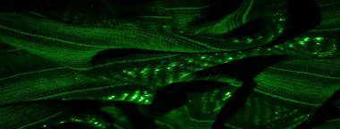 Parlak dokusu ve dokuması olan yeşil kumaş bulanıklığı. Işık karmaşık kumaş deseninden yansıyarak katmanlarda ve katmanlarda derinlik ve detay oluşturur..