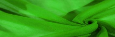 Yumuşak, akışkan yeşil kumaş, doğal katlar halinde düzenlenmiş, malzemelerin hafifliğini ve dokusunu gözler önüne seriyor. Parlak, canlı renk bileşime enerji ve hareket katar..