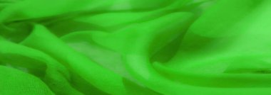 Yumuşak, pürüzsüz kıvrımlı bulanık yeşil kumaş, dinamik bir doku ve biçim oyunu sunuyor. Yumuşak örtü, maddenin esnekliğini vurguluyor, hafiflik hissi uyandırıyor..