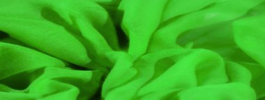 Yumuşak, canlı yeşil kumaş bulanıklığı karmaşık kıvrımlar ve kıvrımlar oluşturuyor. Hassas malzeme ve şeffaf kalitesi görüntüde bir derinlik ve incelik hissi yaratıyor..