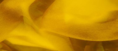 Zarif kıvrımlar ve dalgalar halinde dizilmiş yumuşak sarı kumaş bulanıklığı. Doku, tekstilin hassas ve havadar doğasını yakalar, ışık yüzeyde soyut bir ekran olarak yansıtır..