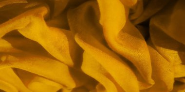 Sarmalanmış sarı kumaşın bulanık görüntüsü ince dokuyu ve şeffaf kaliteyi gösteriyor. Sarmal desen, sıcak sarı renklerde narin ve zarif bir kompozisyon oluşturuyor.