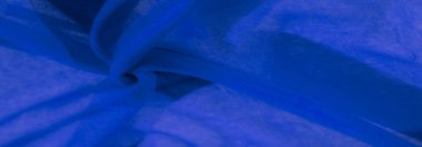 Derin mavi kumaş örtüsü ve kıvrılarak yumuşak dalgalara dönüşüyor. Malzemenin şeffaf kalitesi ışığın bu soyut kompozisyonda derinlik ve akıcılık hissi vererek içinden geçmesine izin verir..