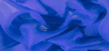 Yumuşak kıvrımlarda dönen zengin mavi kumaş bulanıklığı. Tekstilin ağ dokusu derinlik ve boyut yaratırken ışık ve gölge akışkan ve soyut bir bileşim oluşturmak için etkileşime girer..