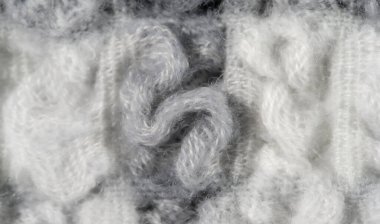 Bulanık - Yumuşak, tüylü beyaz ve gri liflerin birbirine dokunduğu yünlü kumaş yakın plan. Karmaşık dokusu ve nötr tonları tekstil için samimi ve davetkar bir his sunuyor.