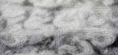 Bulanık kumaş dokusunda gri ve beyaz tonlarda kabarık desenler var. Yumuşak yün kumaş sanatsal olarak dokunmuş, tekstil yüzeyinin rahat ve katmanlı doğasını sergiliyor..