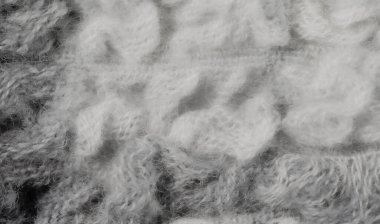 Bulanık beyaz ve gri yün lifleri kabarık, rahat bir kumaş oluşturmak için örülmüş. Yakın çekim dokusu, sıcak, rahat tekstil için ideal, narin bir tasarımı ortaya koyuyor..