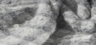 Gri tonlu kumaş deseni bulanıklığı, dokuma liflerinin ince karmaşıklığını yakalıyor. Yumuşak, kabarık dokusu ışığın ve gölgenin etkileşimiyle gelişir.,