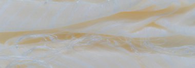 Yumuşak dokuya sahip bulanık sarı kumaş gevşek şeffaf ipliklerle örtülmüş. Kumaşın pürüzsüz, akıcı bir görünüşü ve hafif bir parıltısı var.