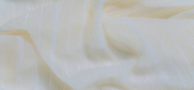 Yumuşak dokuya sahip bulanık sarı kumaş gevşek şeffaf ipliklerle örtülmüş. Kumaşın pürüzsüz, akıcı bir görünüşü ve hafif bir parıltısı var.