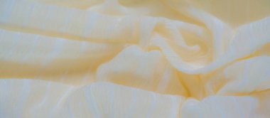 İnce çizgileri ve parlak kıvrımları olan bulanık sarı kumaş. Hafif, pürüzsüz doku ışığı yakalar, ılık ve sakin bir atmosfer yaratır, kumaş zarif bir şekilde yumuşak dalgalarla örtülmüştür..