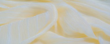 Bulanık, yumuşak kıvrımlı sarı kumaş, narin çizgiler ve çizgiler yumuşak bir doku oluşturuyor. Yumuşak renkler ve açık renk kırışıklıkların birleşimi maddeye akıcı ve huzurlu bir görünüm verir..