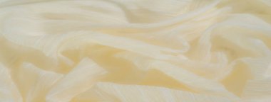Yüzeyine yayılmış ince beyaz iplikleri olan yumuşak sarı kumaş bulanıklığı. Kumaşın pürüzsüz kıvrımları ve hassas dokusu bu soyut kompozisyonda sakin ve sanatsal bir akış yaratır..
