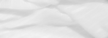 Görüntü. Yumuşak, dalgalı bir dokusu ve ışıldayan bir yüzeyi olan narin beyaz kumaş. Kumaş, karmaşık kıvrımları ve ışık yansımalarıyla akışkan bir hareket ve zarafet hissi yaratır..