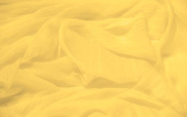 Sarı kumaşın bulanık görüntüsü ince ve dokulu yüzeyini gösteriyor. Yumuşak kıvrımlar gölgelerin etkileşimini yaratır. Parlak, neşeli kumaşa derinlik ve hareket katar..