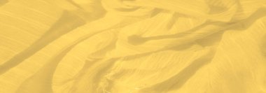 Karmaşık dokuları olan bulanık, parlak sarı kumaş zarif bir şekilde akar, ışığı güzel yansıtan yumuşak dalgalanan desenler sergiler, hareket hissi verir..