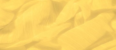 Yumuşak dalgalar ve kırışıklıklarla vurgulanmış parlak sarı bir kumaşın bulanıklığı. Hafif kumaş, hafif kıvrımları ve doğal örtüsüyle ışıldayan, ruhani bir görüntü yaratır..