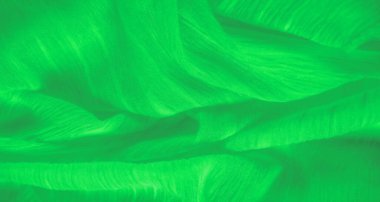Canlı yeşil kumaştan bulanık, ince ince sarmalanmış ışık altında parıldayan ipliklerle, pürüzsüz, akışkan bir yüzey ve ince doku katmanları yaratıyor..