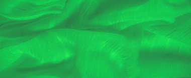 Yumuşak, akıcı bir dokuyla kaplanmış canlı yeşil kumaş bulanıklığı. Yüzeyde ince iplikler dokularak tekstil üzerinde dinamik bir ışık ve gölge etkileşimi yaratır.