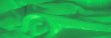 Yumuşak kıvrımlara dolanmış parlak iplikleri olan yeşil kumaş bulanıklığı. Parlak doku ve soyut ışık enerjik ve dinamik bir desen yaratır..