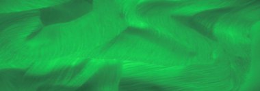 Yüzeyinde dalgalanan yumuşak dalgalarla canlı yeşil bir kumaşın bulanıklığı. Işık, zengin dokuyu geliştirir ve tekstil içindeki hareketi vurgular.