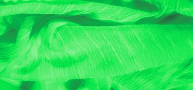 Canlı yeşil kumaş, karmaşık iplik detayları ve pürüzsüz, parlak bir yüzey. Dinamik kıvrımlar, tekstil ve soyut tasarım kavramları için ideal görsel olarak çarpıcı bir kompozisyon oluşturur..