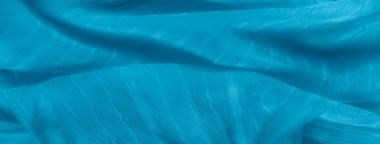 İnce ipliklerle kaplı narin mavi kumaş dokuyu ve derinliği ekliyor. Birbirine dolanmış lifler, pürüzsüz tekstil arka planına dinamik bir his veriyor..