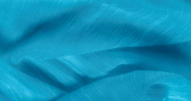 Yumuşak dalgaları ve kıvrımları olan pürüzsüz mavi kumaş, ince detaylı bir doku sergiliyor. İnce kıvrımlar ve ışık vurguları yumuşak tekstil yüzeyine boyut ekler.