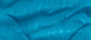 Yumuşak, dalgalı kıvrımları ve ince dokusu olan açık mavi kumaş bulanıklığı. Kumaşın doğal akışı rahatlatıcı ve sakin bir soyut tasarım yaratarak hassas materyali vurguluyor..