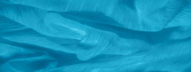 Yumuşak, dalgalı kıvrımları ve ince dokusu olan açık mavi kumaş bulanıklığı. Kumaşın doğal akışı rahatlatıcı ve sakin bir soyut tasarım yaratarak hassas materyali vurguluyor..