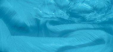 Dalgalanan, yumuşak dalgalanmalar ve ince detaylarla karışık mavi kumaş. Birbirine dolanmış iplikler kumaş içinde dokulu ve dinamik bir soyut kompozisyon oluşturur..